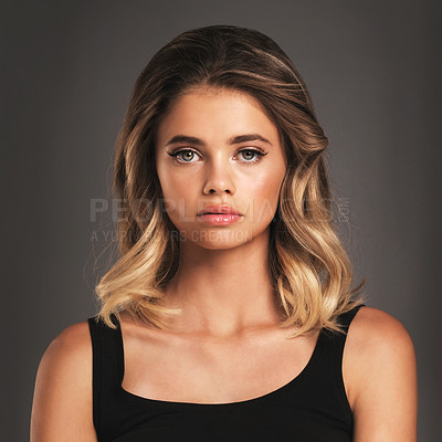 Buy stock photo Studio portrait of an attractive young woman posing against a dark background