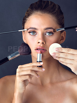 Buy stock photo Studio shot of an attractive young woman posing while cosmetics are applied on her face