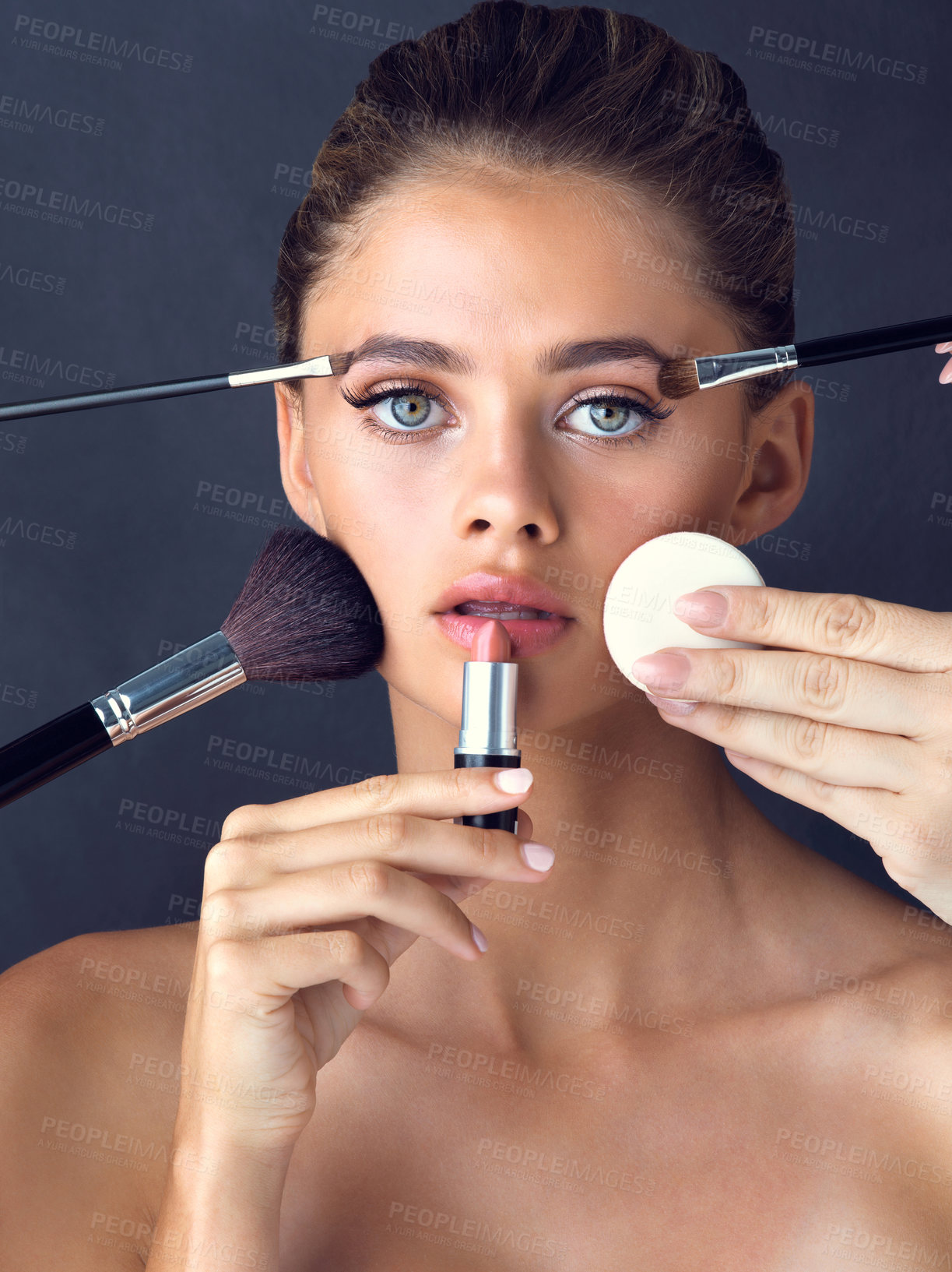 Buy stock photo Studio shot of an attractive young woman posing while cosmetics are applied on her face