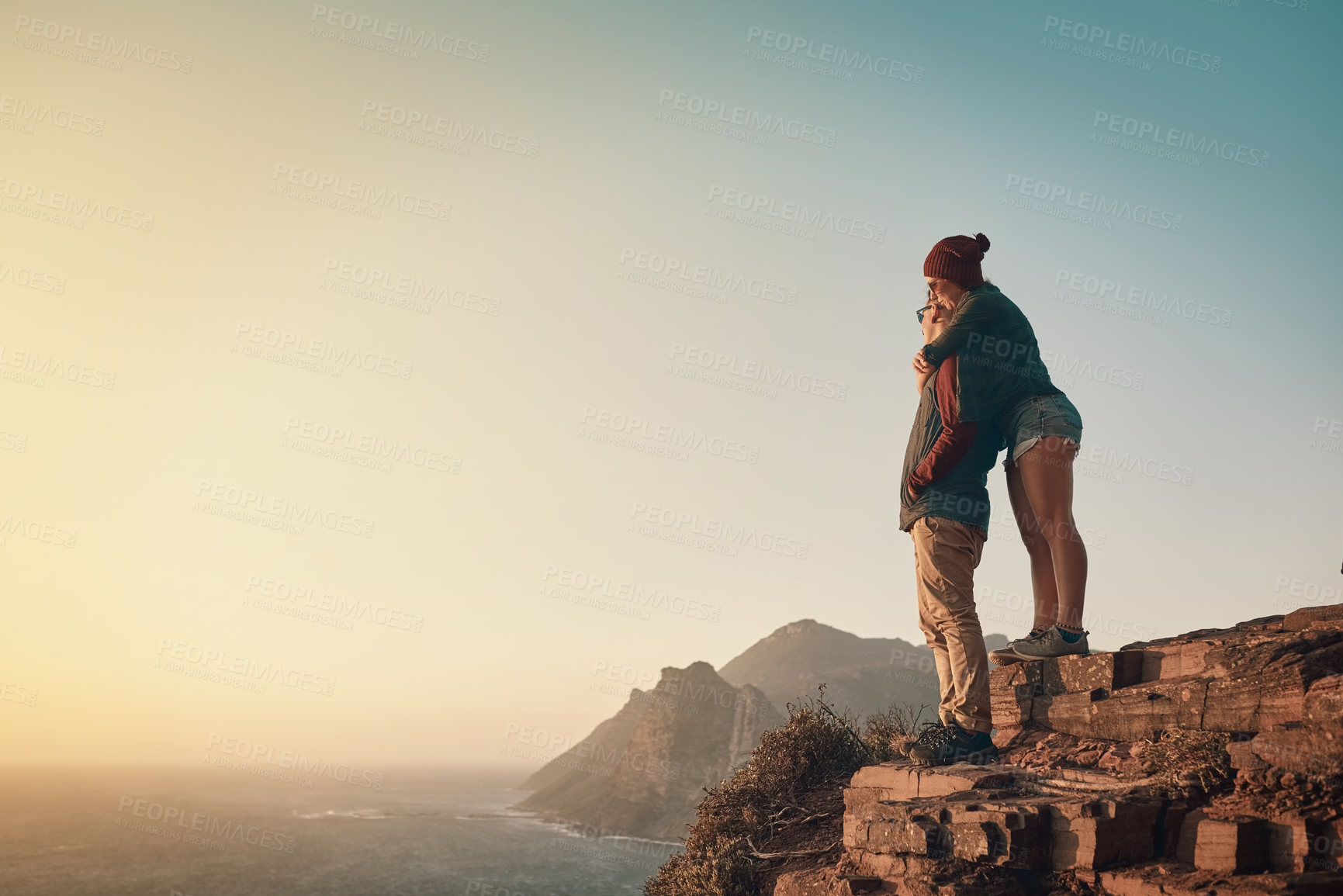 Buy stock photo Full length shot of an affectionate young couple taking in the view from a mountaintop