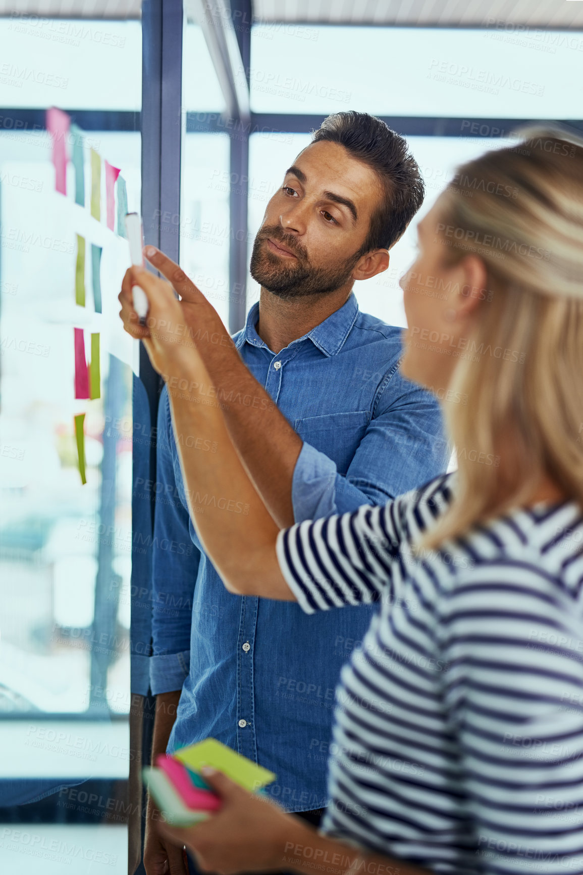 Buy stock photo Shot of two colleagues having a brainstorming session in a modern office