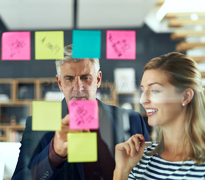 Buy stock photo Shot of two colleagues having a brainstorming session in a modern office