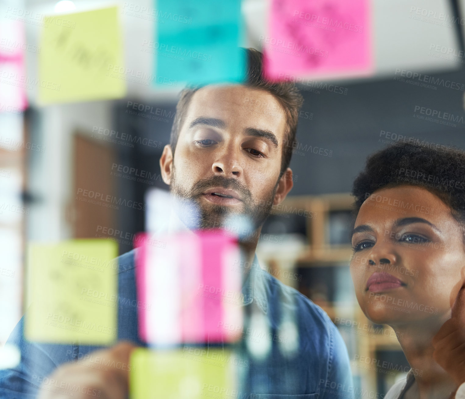 Buy stock photo Shot of two colleagues having a brainstorming session in a modern office