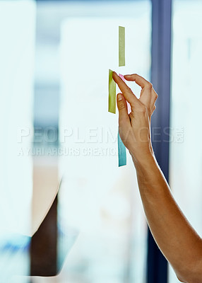 Buy stock photo Cropped shot of a woman pasting notes on glass during a brainstorming session at work