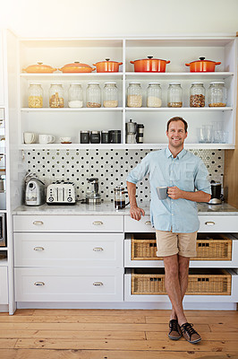 Buy stock photo Shot of a laid-back bachelor enjoying a cup of coffee in his kitchen at home