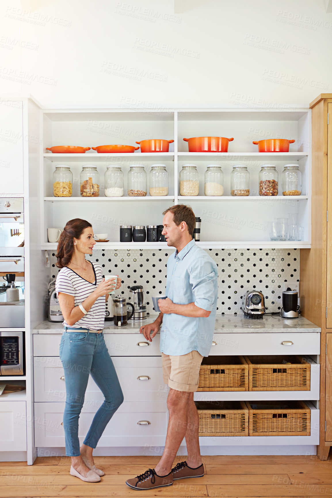 Buy stock photo Shot of a happy married couple enjoying a cup of coffee together in their kitchen at home