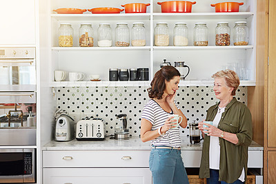 Buy stock photo Shot of a woman and her elderly mother catching up over coffee in the kitchen