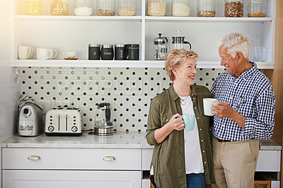 Buy stock photo Shot of a happy senior couple bonding over coffee in their kitchen at home