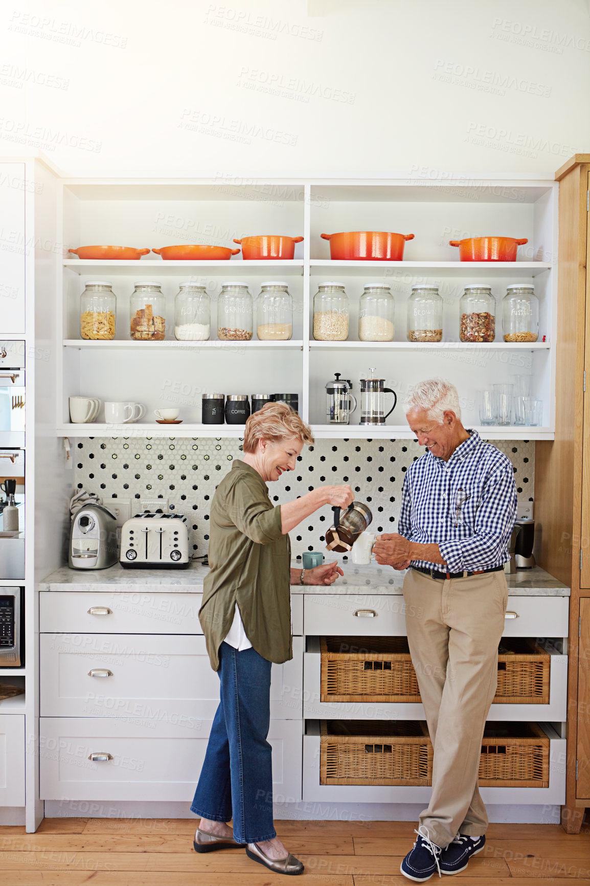 Buy stock photo Shot of a happy senior couple bonding over coffee in their kitchen at home