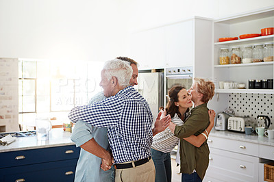 Buy stock photo Shot of a loving family greeting each other with hugs in the kitchen at home