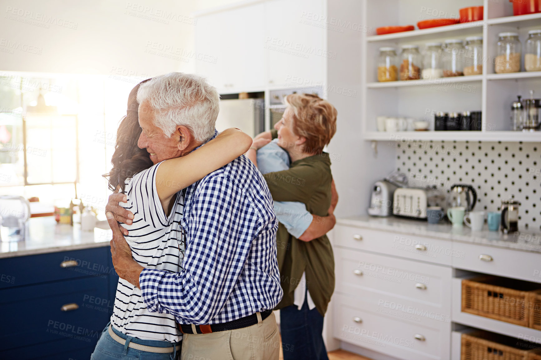 Buy stock photo Shot of a loving family greeting each other with hugs in the kitchen at home