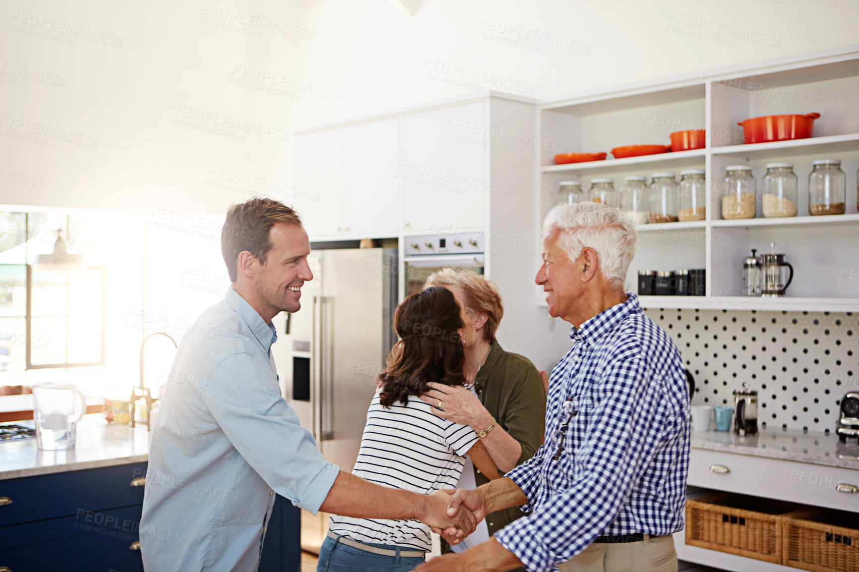 Buy stock photo Shot of a loving family greeting each other with hugs in the kitchen at home