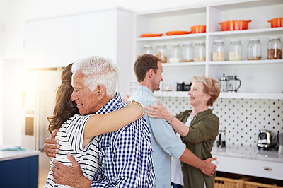 Buy stock photo Shot of a loving family greeting each other with hugs in the kitchen at home