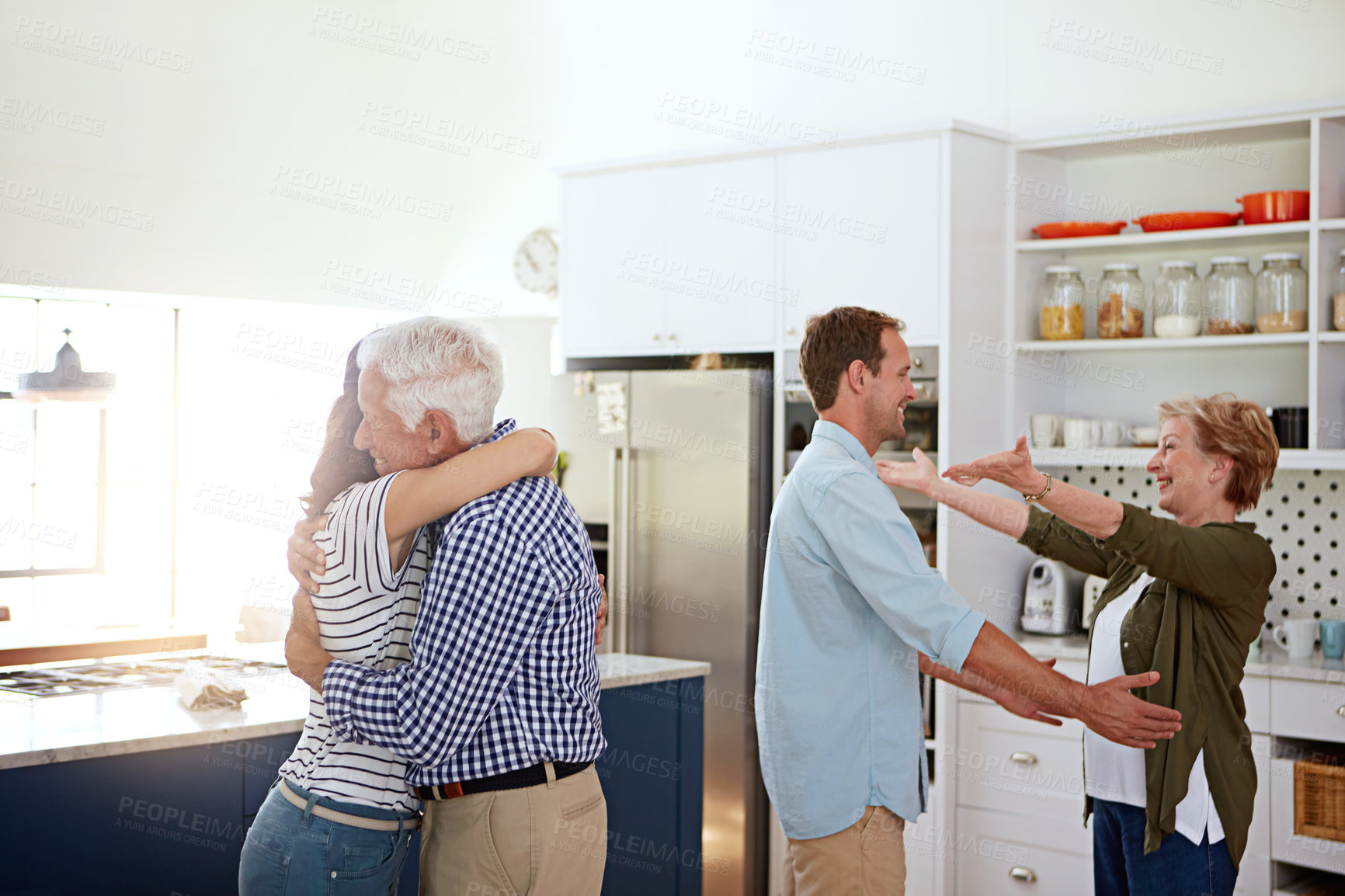 Buy stock photo Shot of a loving family greeting each other with hugs in the kitchen at home