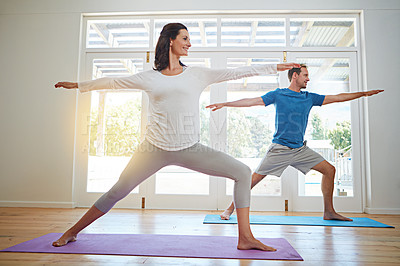 Buy stock photo Full length shot of a mature couple practicing yoga in their home