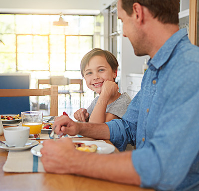 Buy stock photo Cropped shot of a young boy enjoying breakfast with his father
