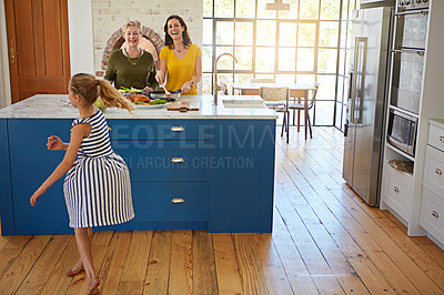 Buy stock photo Shot of a little girl dancing while her mother and grandmother cooks in the background