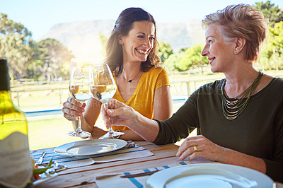 Buy stock photo Shot of a senior mother and her daughter toasting with wine during a family lunch outdoors
