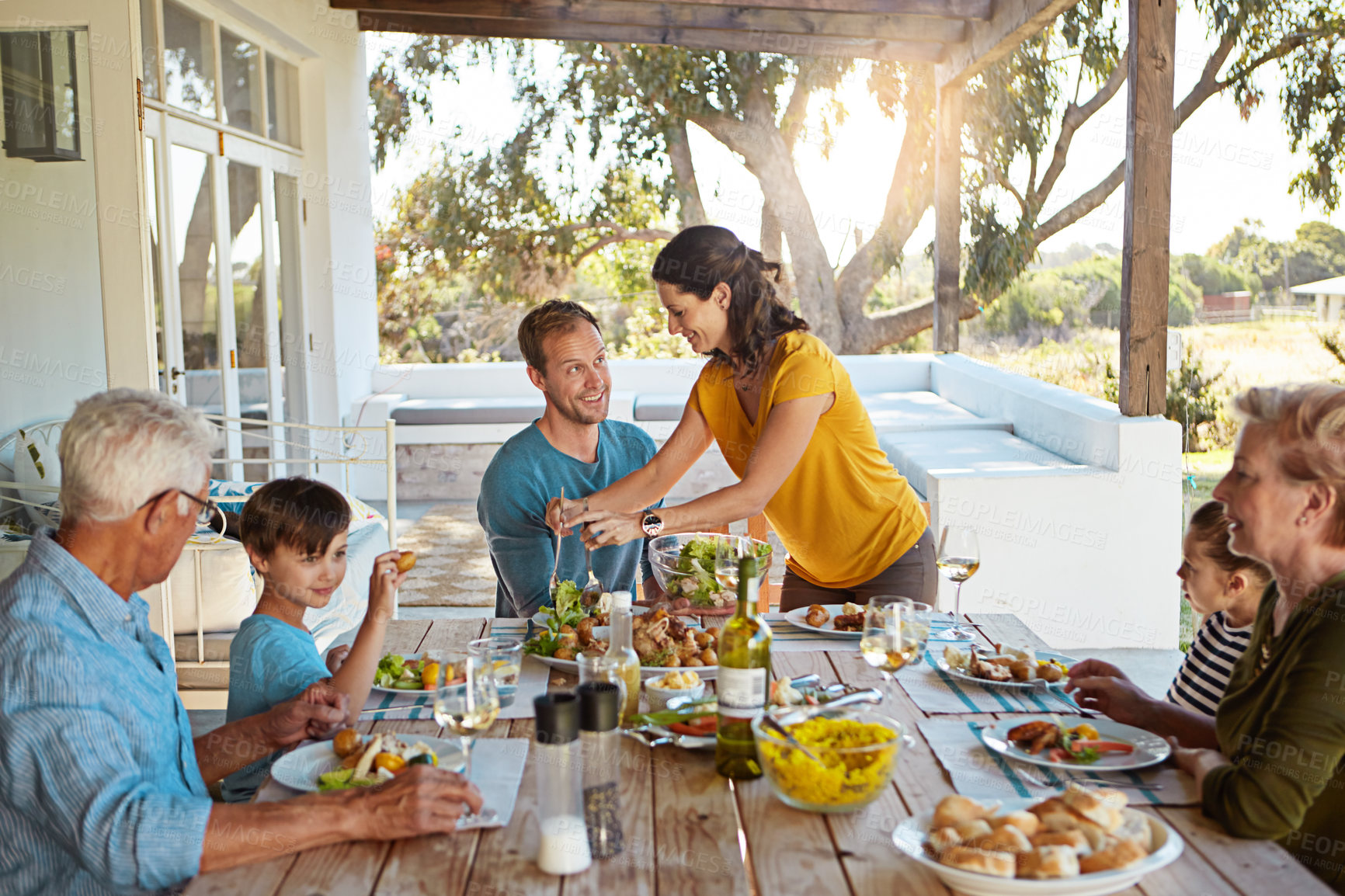 Buy stock photo Big family, eating and food with relax outdoor on patio with conversation, bonding and healthy meal in summer. Parents, grandparents and kids at dining table in backyard of home with talking or fun