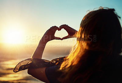 Buy stock photo Rearview shot of a woman making a heart shape with her hands outside