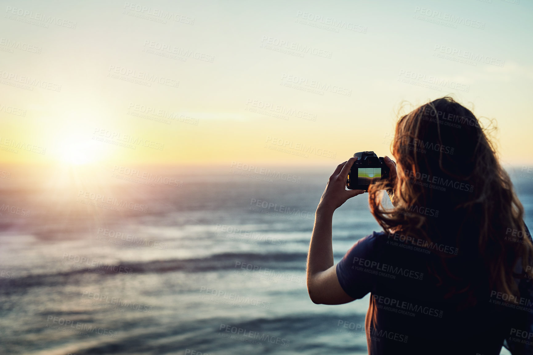 Buy stock photo Beach, sunset or girl with camera in nature for photography, memory or scenic capture on summer, trip or vacation. Lens, sea or woman back with digital photo of ocean, water or sunrise travel moment