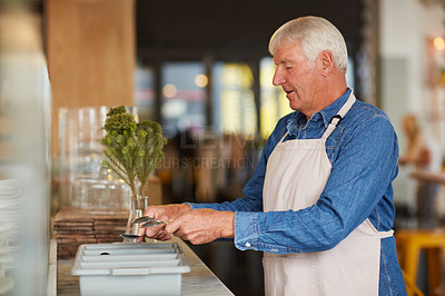 Buy stock photo Shot of a happy senior business owner sorting cutlery in his coffee shop