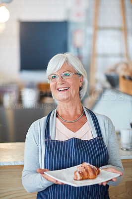Buy stock photo Shot of a happy senior business owner holding a plate with a pastry on it in her coffee shop