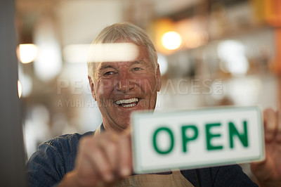 Buy stock photo Shot of a happy senior business owner holding up an open sign in the door of his coffee shop