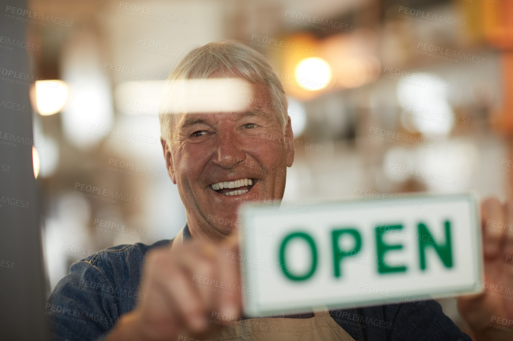 Buy stock photo Shot of a happy senior business owner holding up an open sign in the door of his coffee shop