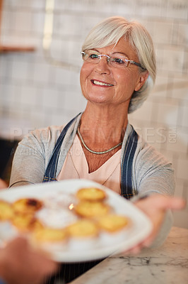 Buy stock photo Shot of a happy senior business owner handing a plate of pastries to a waiter in her coffee shop