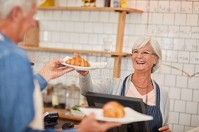 Buy stock photo Shot of a happy senior business owner handing a plate of pastries to a waiter in her coffee shop