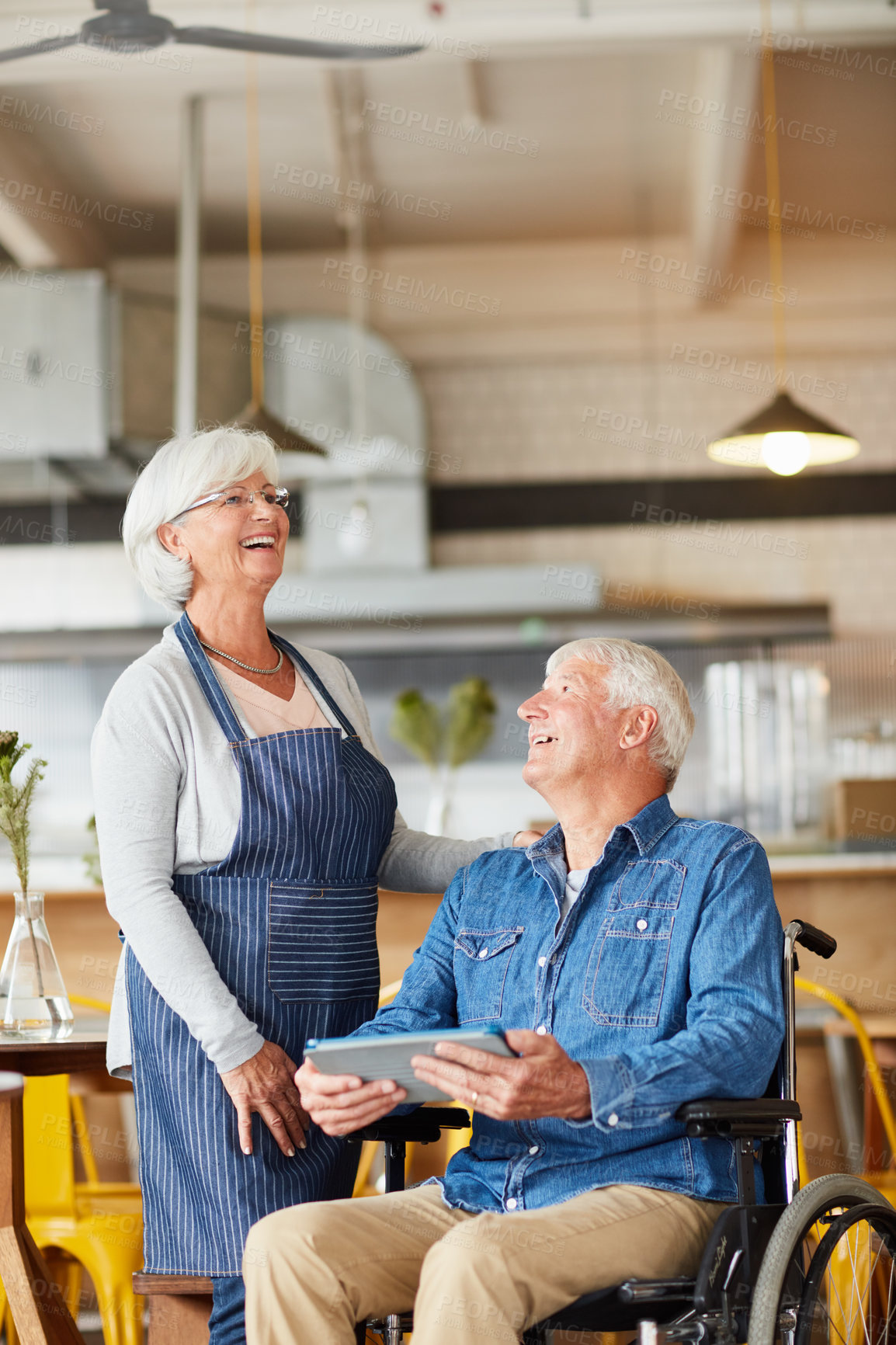 Buy stock photo Shot of two senior business owners looking at a tablet together while working in their coffee shop