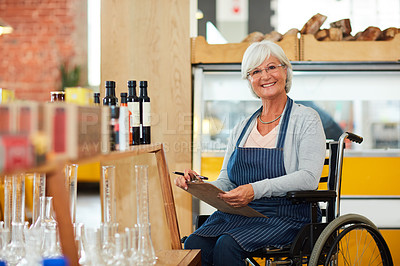 Buy stock photo Portrait of a senior woman in a wheelchair doing stock take in her coffee shop