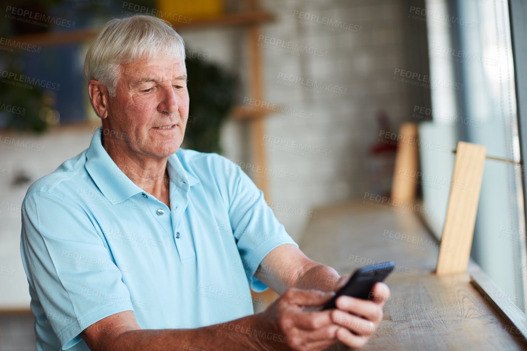 Buy stock photo Cropped shot of a senior man using his cellphone while sitting in a coffee shop
