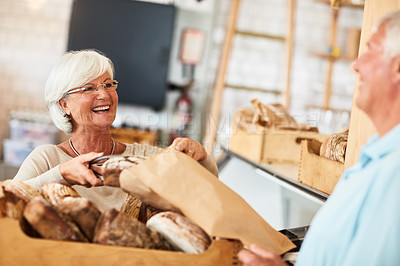 Buy stock photo Shot of a happy senior woman serving a customer in a bakery