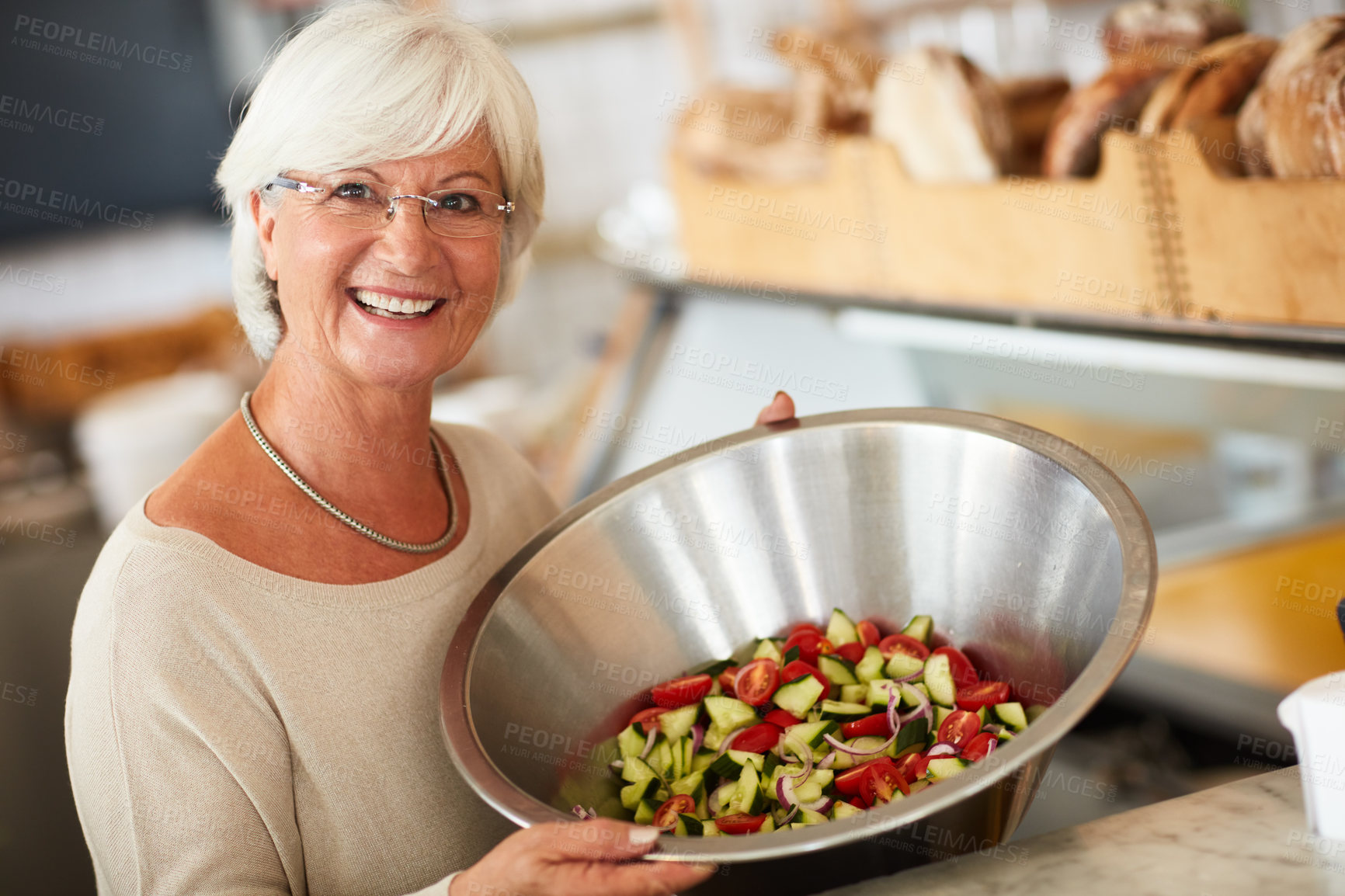 Buy stock photo Portrait of a happy senior woman holding a bowl of freshly chopped vegetables in a store