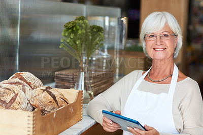 Buy stock photo Portrait of a happy senior woman using a digital tablet to manage her bakery