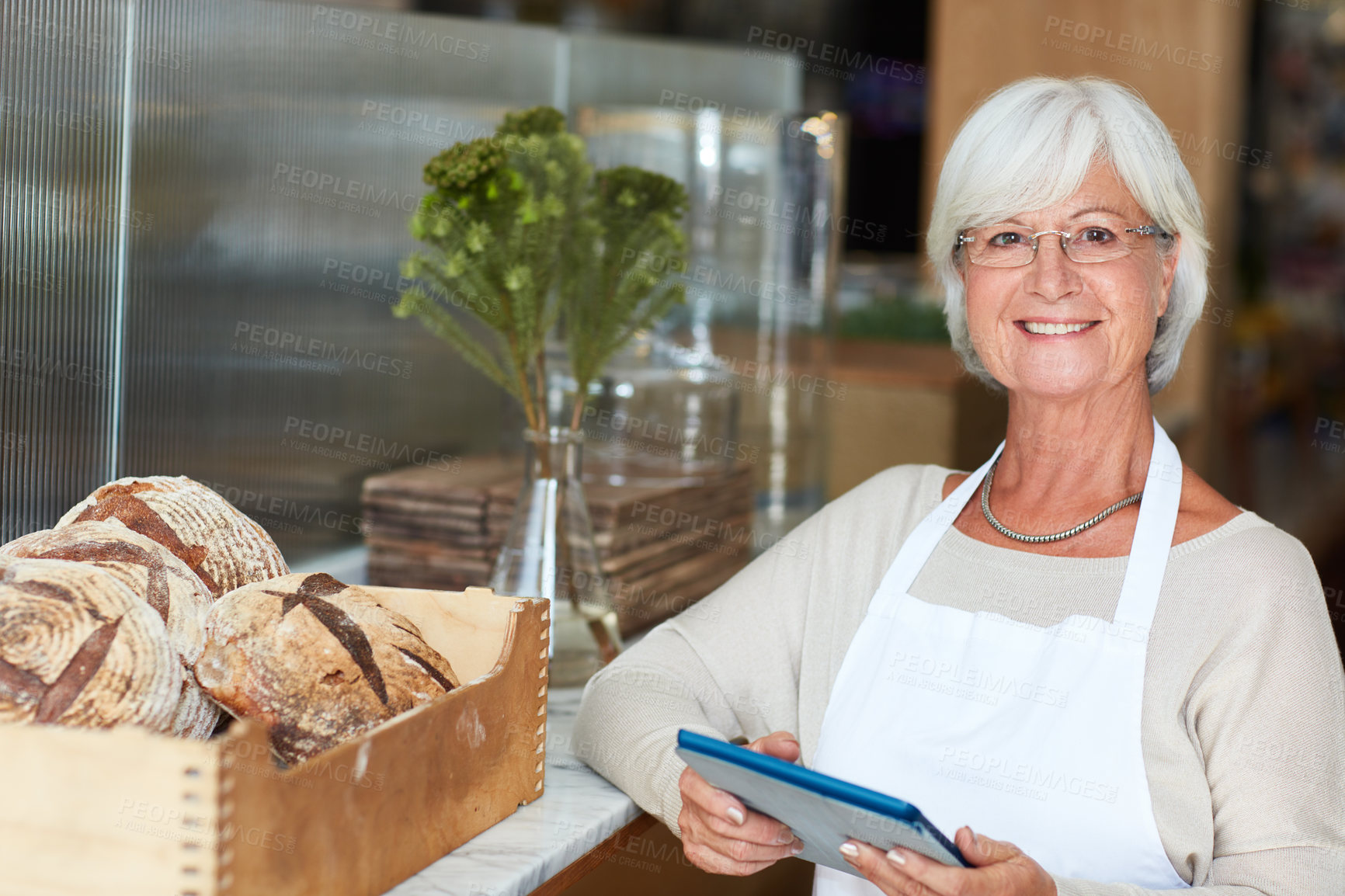 Buy stock photo Portrait of a happy senior woman using a digital tablet to manage her bakery