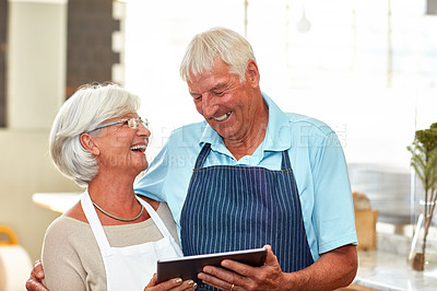 Buy stock photo Shot of a happy senior couple using a digital tablet to manage their small business