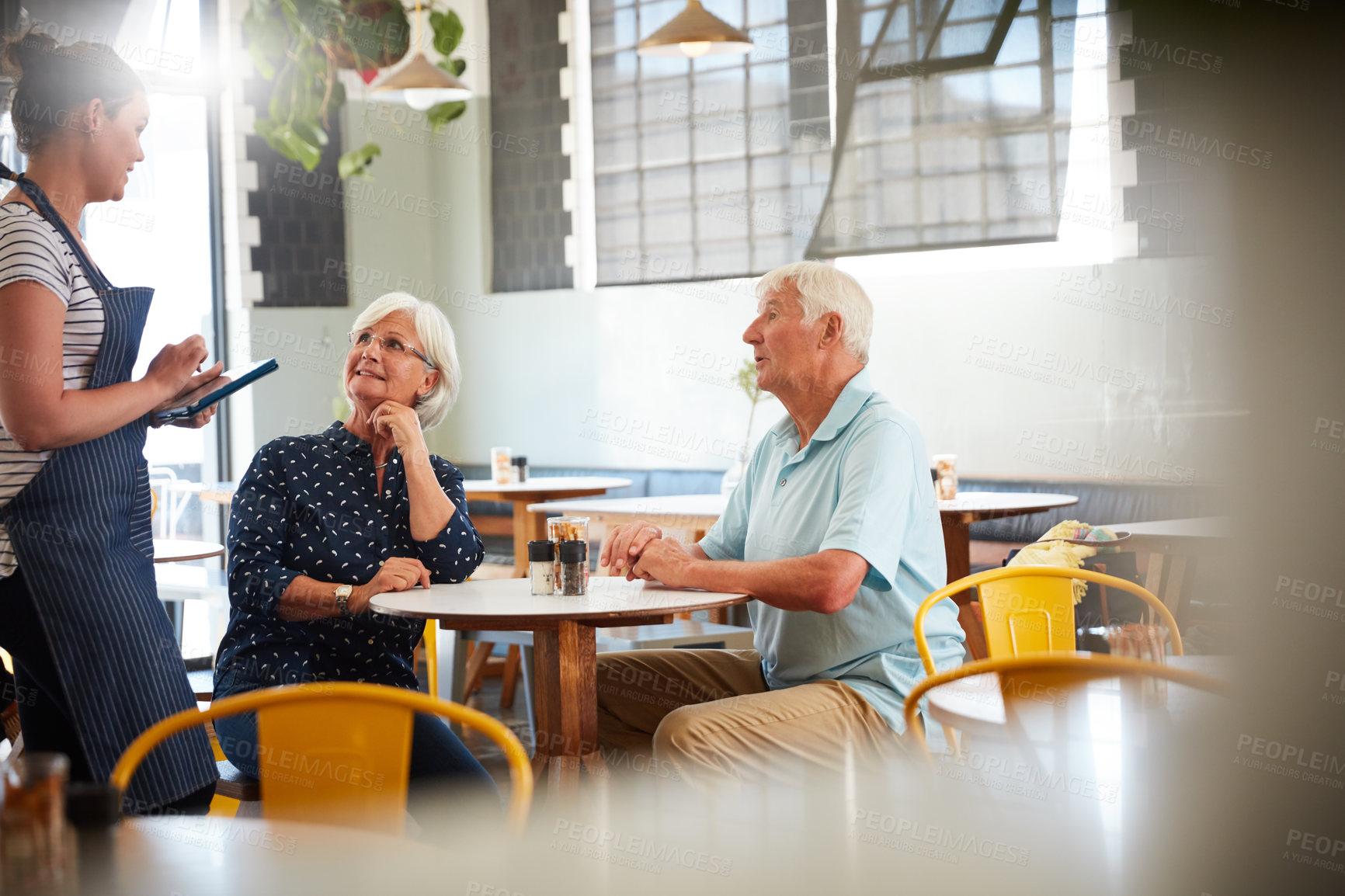 Buy stock photo Cropped shot of a senior couple being served by a waitress