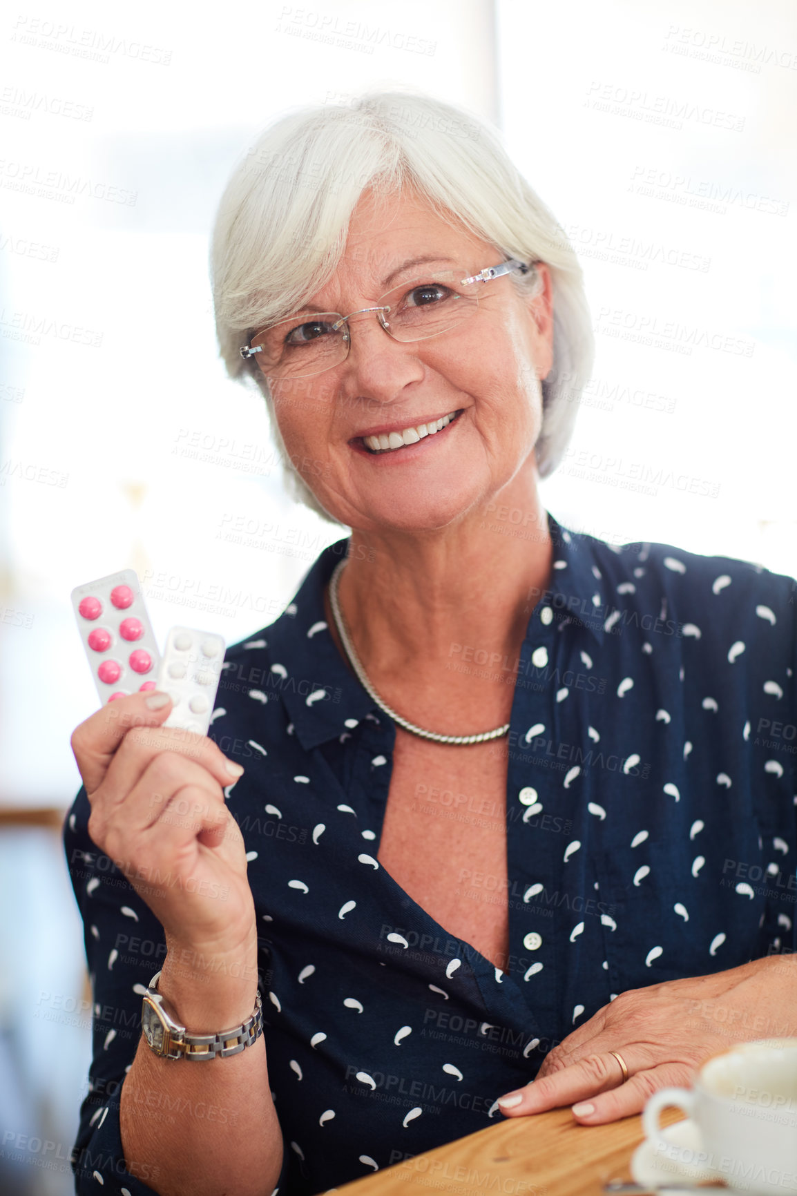 Buy stock photo Cropped shot of a senior her holding up her medication while sitting in a cafe
