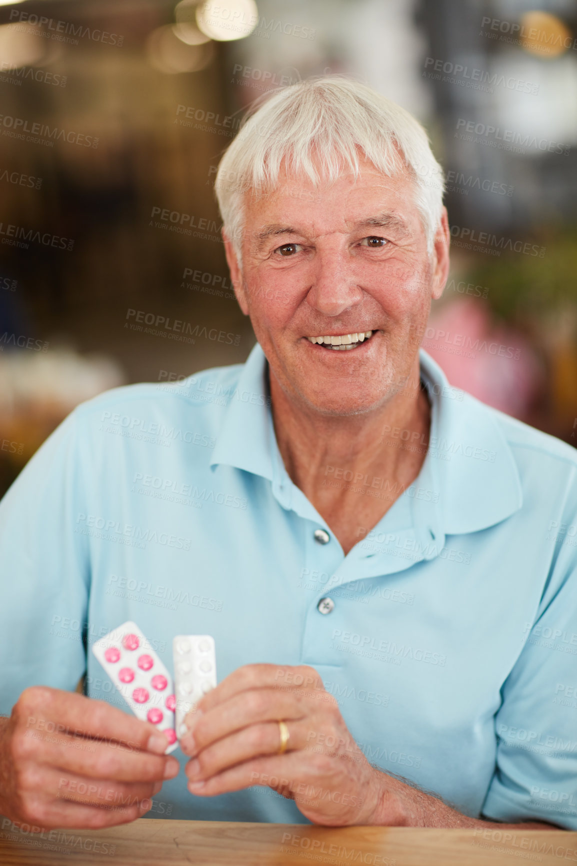 Buy stock photo Cropped shot of a senior man holding up his medication while sitting in a cafe