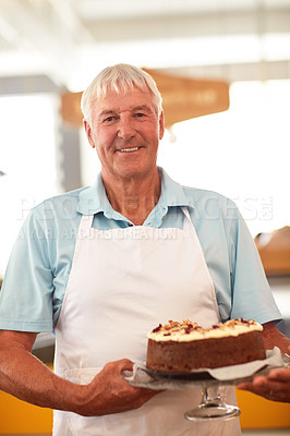 Buy stock photo Portrait of a happy senior man holding a freshly baked cake in his bakery