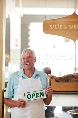 Buy stock photo Shot of a happy senior man holding up an open sign in his bakery