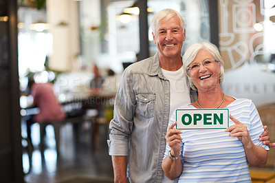 Buy stock photo Portrait of a happy senior couple holding up an open sign in their store