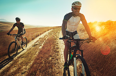 Buy stock photo Shot of two cyclists out cycling in the countryside