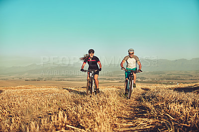 Buy stock photo Shot of two cyclists out cycling in the countryside