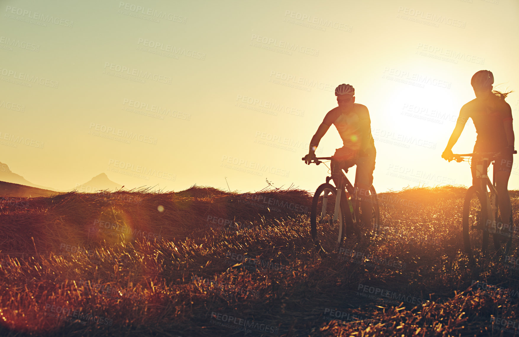 Buy stock photo Sunset, people and team in bicycle race with helmet, exercise and adventure trail in nature together. Cycling, fitness and friends with mountain bike in evening for outdoor workout, energy and mockup