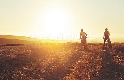 Buy stock photo Sunset sky, people and team on bicycle path with grass, exercise and adventure trail in nature together. Cycling, fitness and friends with mountain bike in evening for outdoor workout, sun and mockup