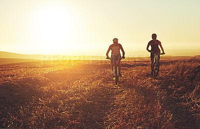 Buy stock photo Sunset, people and team on bicycle in countryside with grass, exercise or adventure trail in nature together. Cycling, fitness and friends on mountain bike for evening outdoor workout, sun and mockup